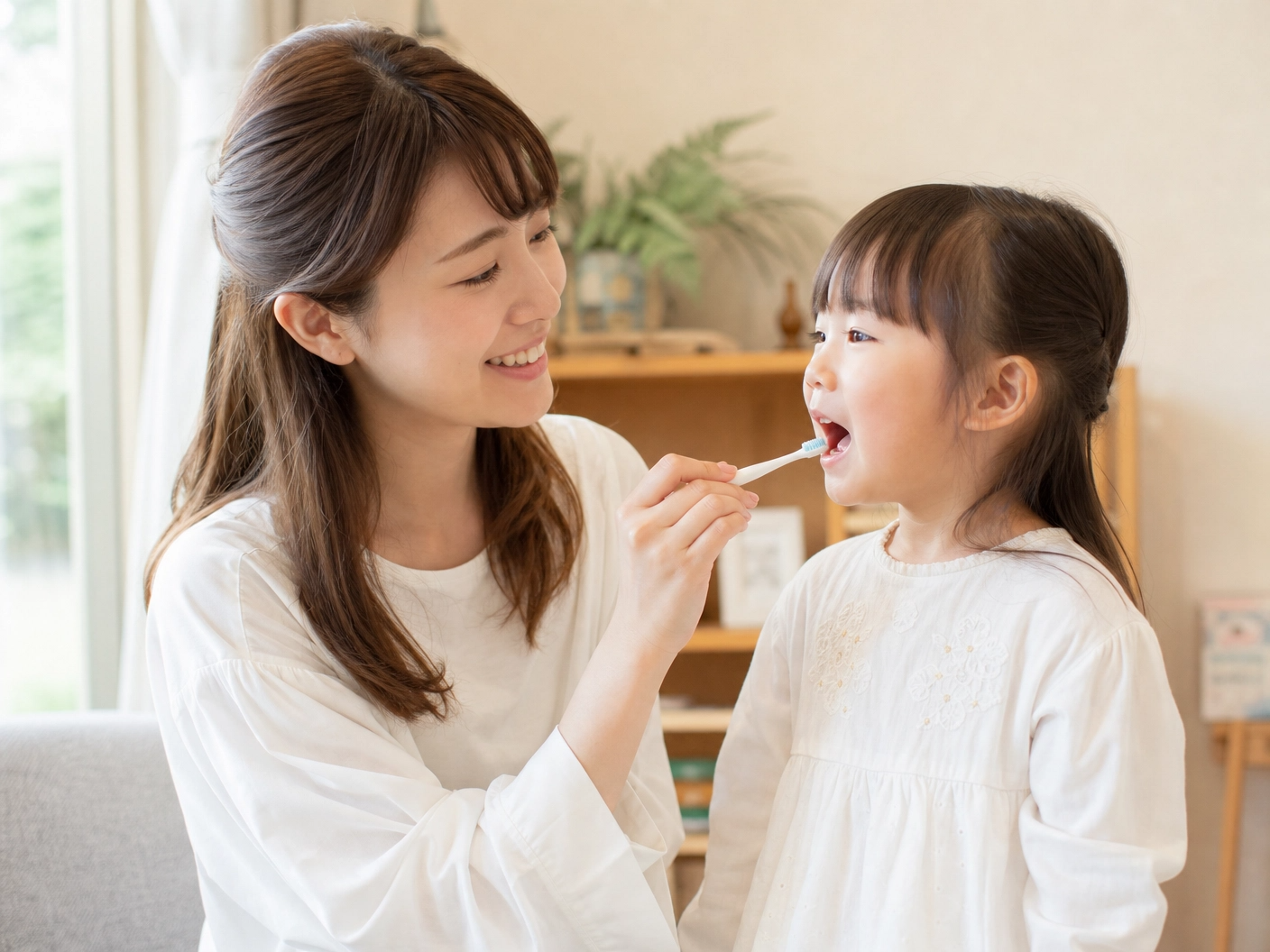 プロンプト：きれいなお母さんが笑顔でお子様の歯磨きを仕上げチェックしている、温かい家庭の日常の一コマの写真。自然光が差し込む明るい部屋。