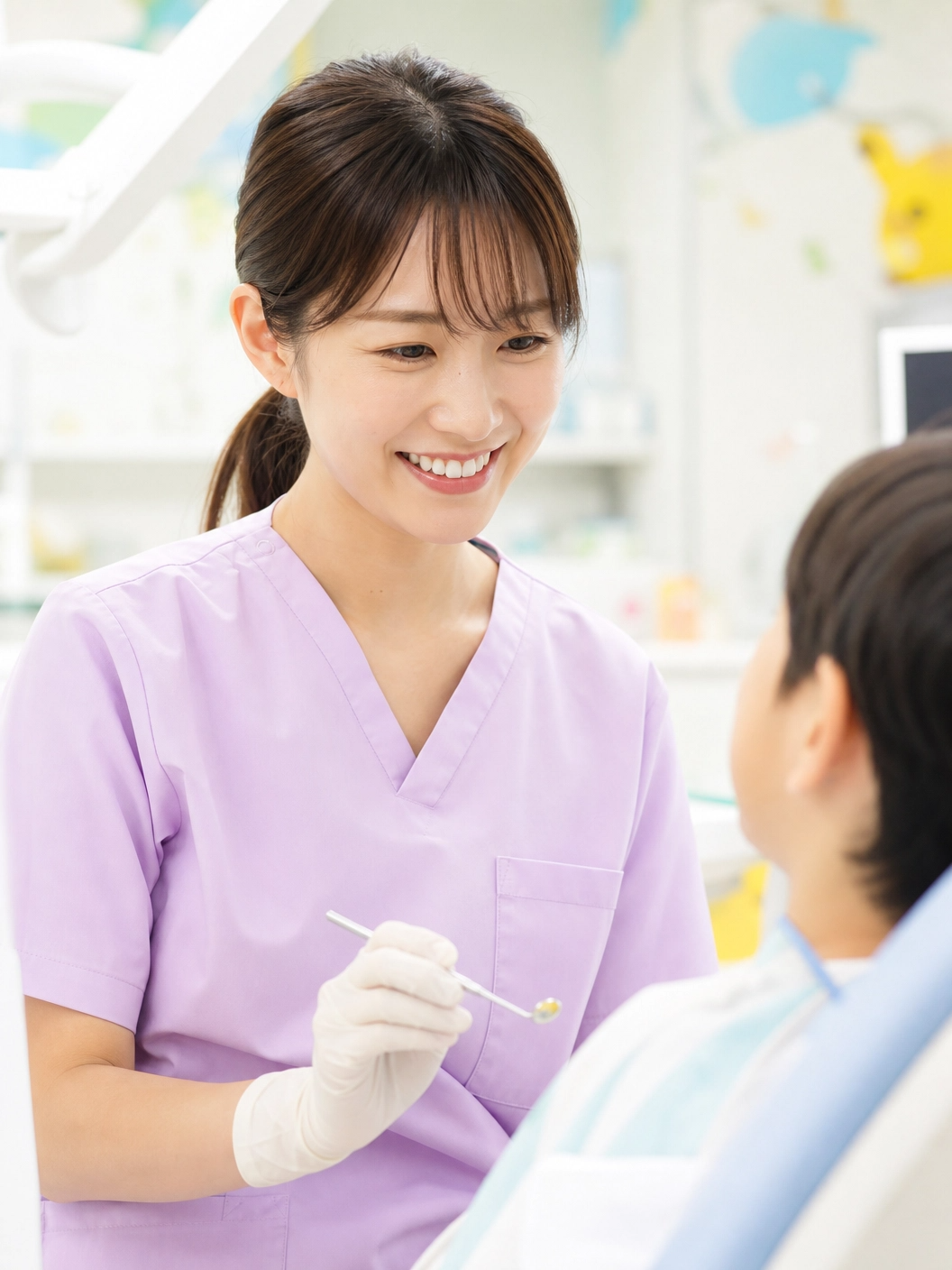 プロンプト：優しい笑顔の女性歯科医師（スクラブ着用）。子どもをリラックスさせるのが得意そうな親しみやすい雰囲気の写真。